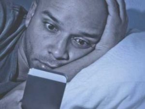 man reading article on aphone in bed